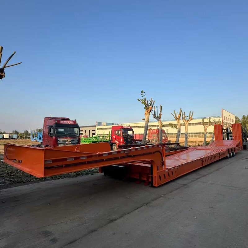 Truck tractor trailer for transporting low flatbed transfer vehicles